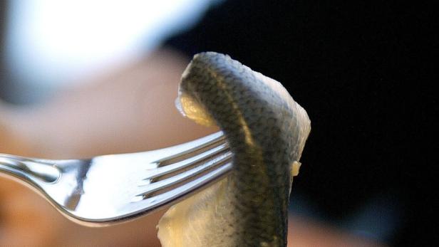 Ein Stück Fisch wird mit einer Gabel gehalten.