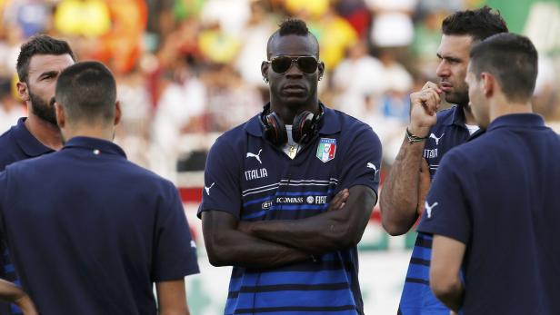 Mario Balotelli mit Sonnenbrille und Kopfhörern inmitten anderer Fußballspieler.