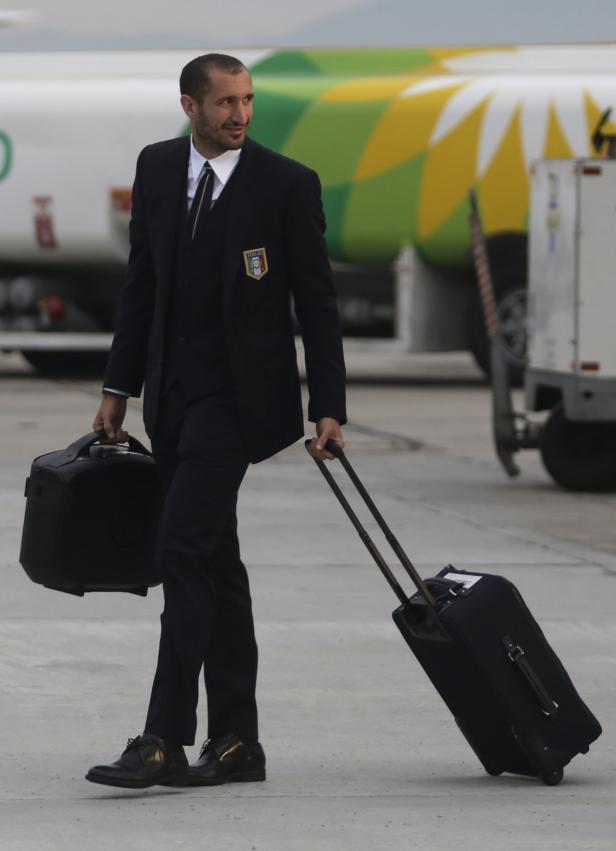 Giorgio Chiellini mit Anzug und Gepäck vor einem Flugzeug.