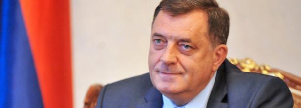 Ein Porträt von Milorad Dodik vor einer blau-rot gestreiften Flagge.