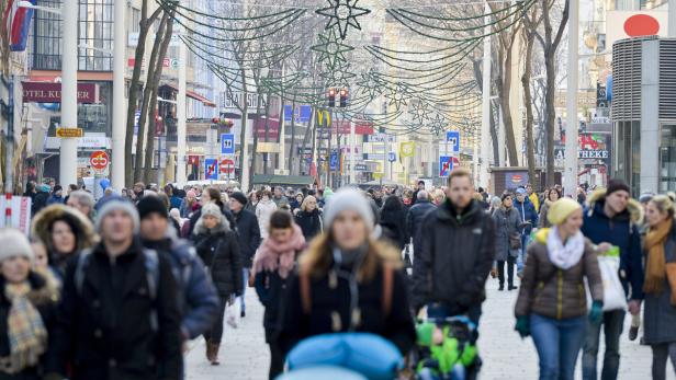 Eine belebte Einkaufsstraße mit vielen Menschen und Weihnachtsdekorationen.