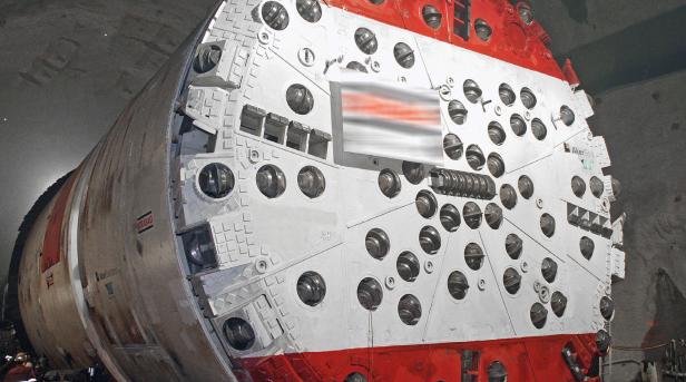 Eine Tunnelbohrmaschine mit rot-weißem Bohrkopf im Einsatz.