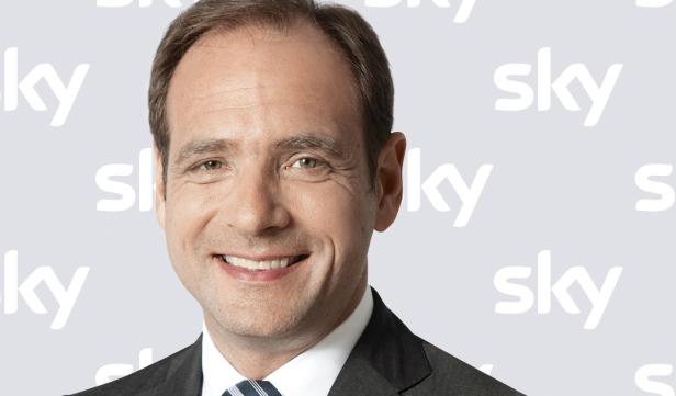 Porträt eines lächelnden Mannes vor einem Hintergrund mit dem Sky-Logo.