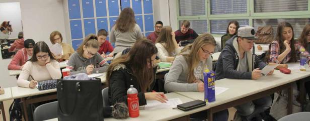 Schüler sitzen in einem Klassenzimmer und schreiben an ihren Tischen.