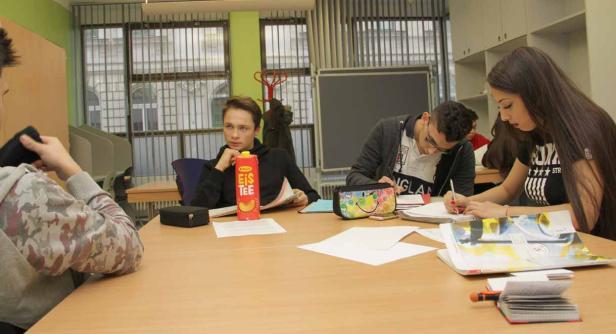 Schüler sitzen in einem Klassenzimmer und arbeiten an ihren Aufgaben.