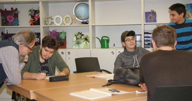 Eine Gruppe von Schülern und ein Lehrer sitzen an einem Tisch in einem Klassenzimmer.