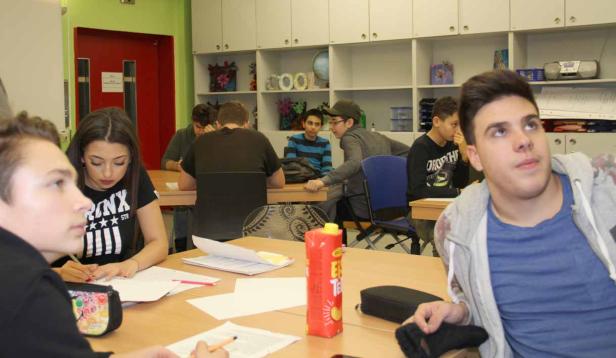Schüler sitzen in einem Klassenzimmer und arbeiten an ihren Aufgaben.