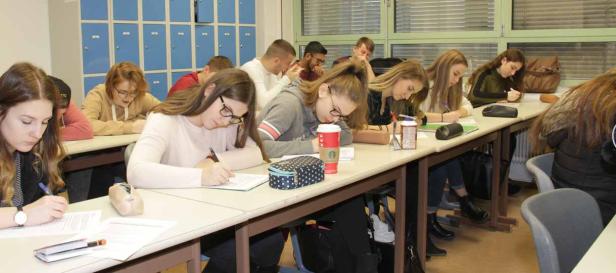 Schüler sitzen in einem Klassenzimmer und schreiben an ihren Tischen.