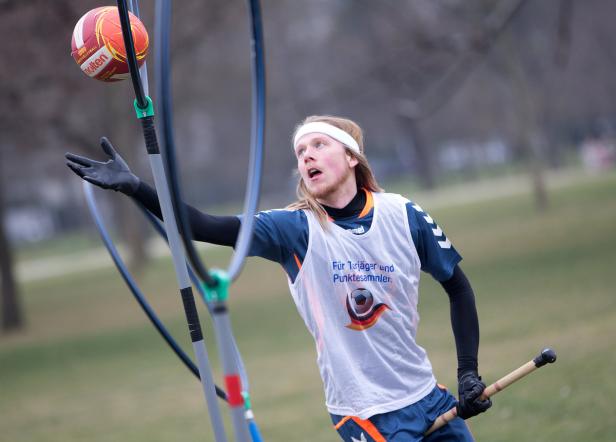 Ein Quidditch-Spieler versucht, einen Ball durch einen der Ringe zu werfen.