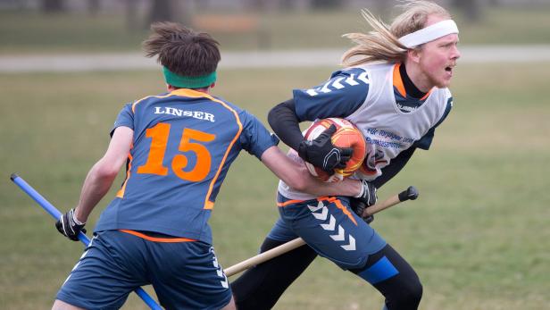Zwei Quidditch-Spieler kämpfen um den Ball auf einem grünen Feld.