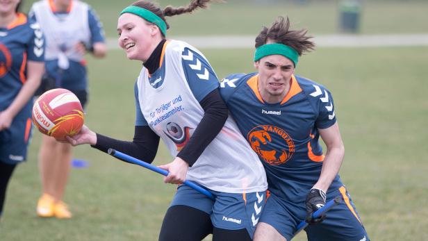 Zwei Quidditch-Spieler kämpfen um den Ball auf einem grünen Feld.