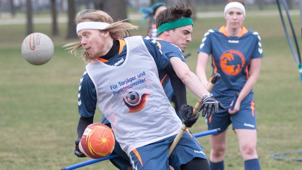 Zwei Quidditch-Spieler kämpfen um den Ball, während eine Mitspielerin im Hintergrund zusieht.