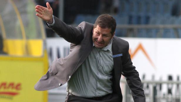 Ein Fußballtrainer gestikuliert auf dem Spielfeld.