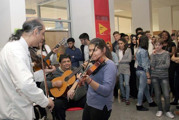 Eine Gruppe von Musikern spielt vor einem Publikum in einem hellen Raum.