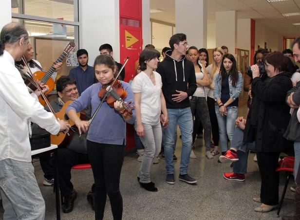 Eine junge Geigerin spielt vor einer Gruppe von Zuhörern, begleitet von Gitarrenmusikern.