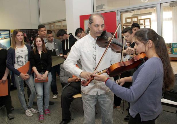 Ein Musiklehrer unterrichtet eine Gruppe von Schülern im Violinenspiel.