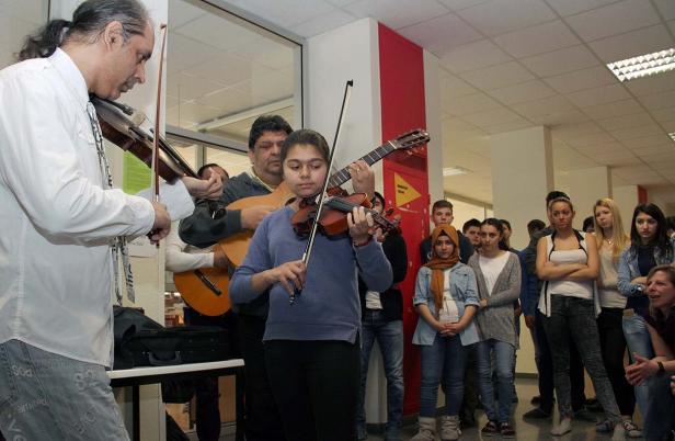 Eine Gruppe von Musikern spielt Geige und Gitarre vor einem Publikum.