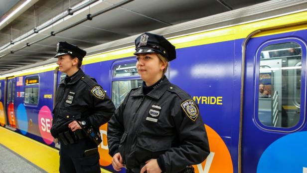 Zwei Polizistinnen der New Yorker Polizei stehen an einem Bahnsteig vor einem Zug.