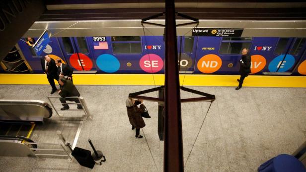 Ein Blick von oben auf einen Bahnsteig der New Yorker U-Bahn mit einem Zug im Bahnhof.