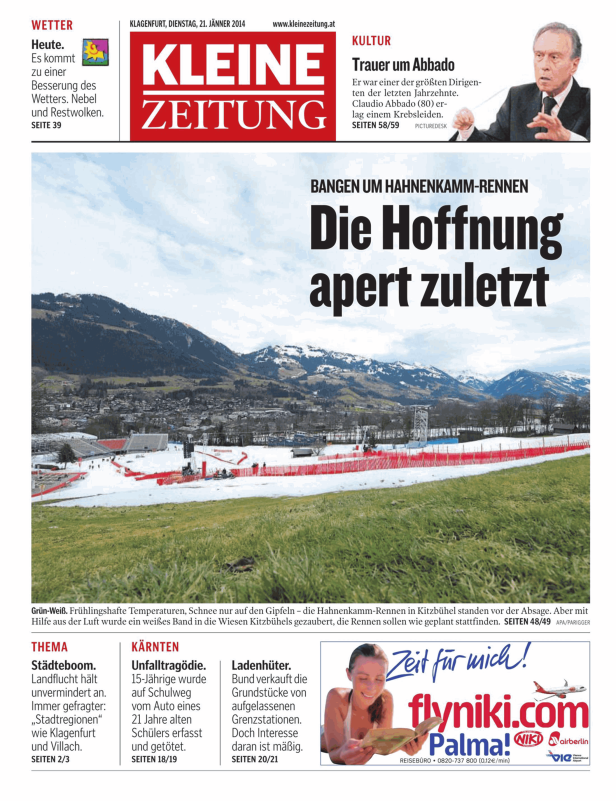 Blick auf Kitzbühel mit Schnee auf den Bergen und einer Skipiste im Vordergrund.