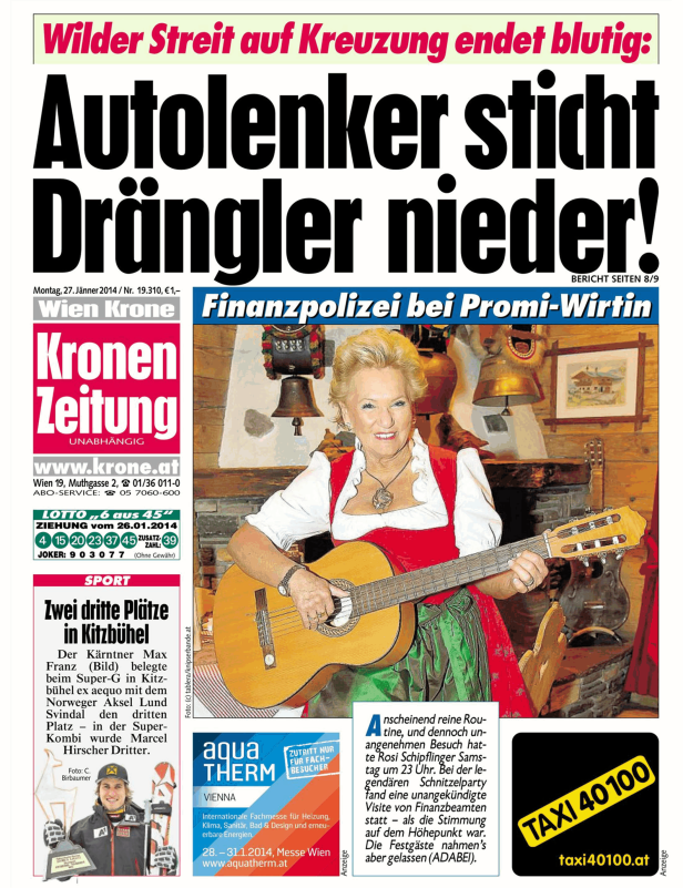 Eine Frau im Dirndl spielt Gitarre vor einer Wand mit Dekorationen.