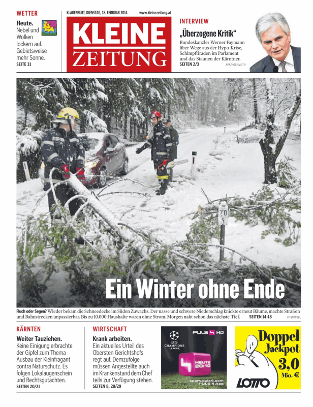 Feuerwehrleute beseitigen im Schnee eine umgestürzte Baumkrone von einer Straße.
