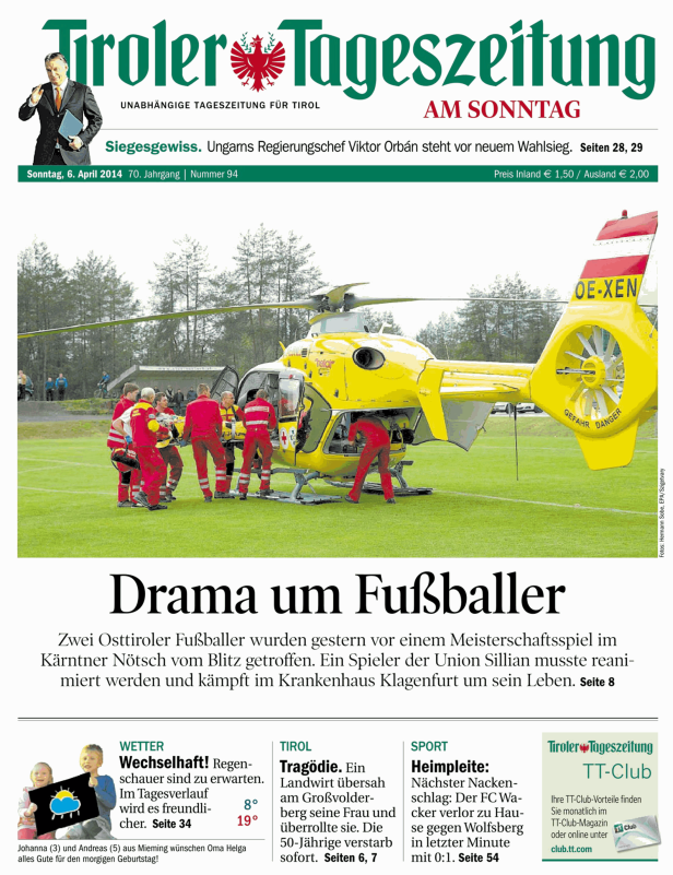 Ein gelber Rettungshubschrauber steht auf einem Fußballfeld, Sanitäter eilen zu Verletzten.