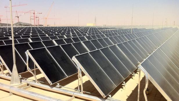 Ein Solarkraftwerk mit vielen Paneelen in einer Wüstenlandschaft.