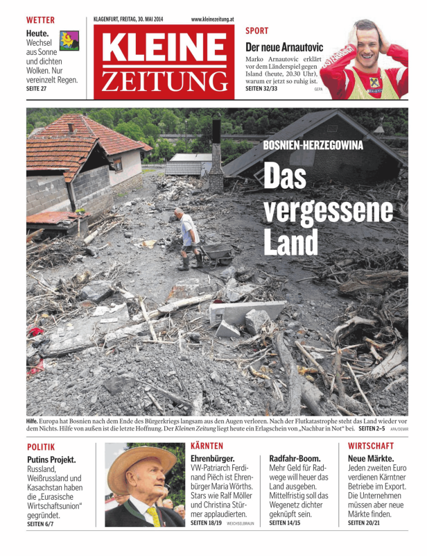 Ein Mann schiebt eine Schubkarre durch eine von Überschwemmungen verwüstete bosnische Landschaft.