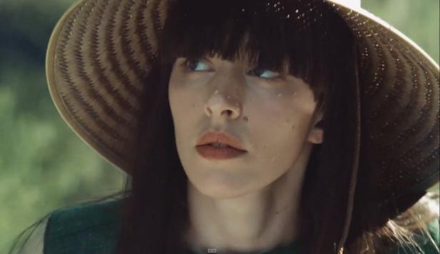 Eine Frau mit Hut blickt in die Ferne.