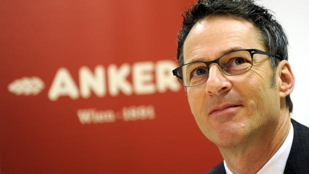 Ein Mann mit Brille vor einem roten Hintergrund mit dem Schriftzug „Anker“.