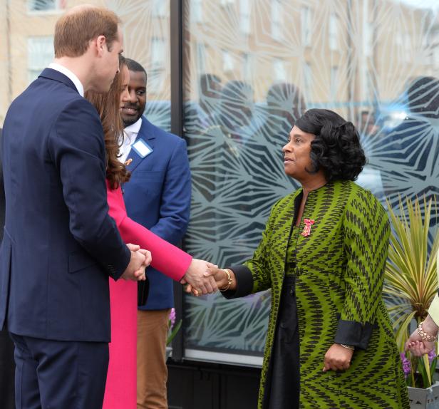 Prinz William und Kate Middleton schütteln einer Frau in einem grün gemusterten Mantel die Hand.