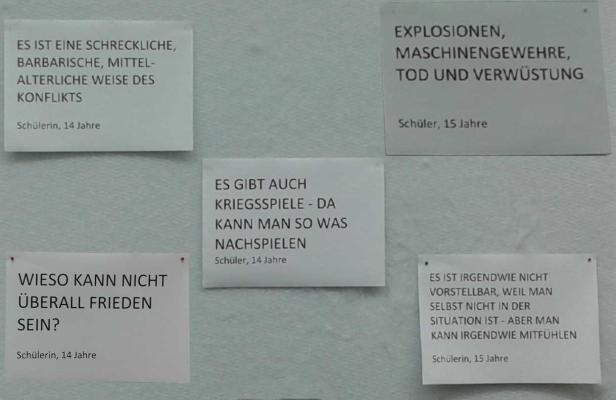 Auf einer Wand hängen Zettel mit Aussagen von Schülern zum Thema Krieg und Frieden.