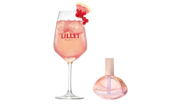 Ein Glas Lillet-Cocktail mit Eis und Johannisbeeren neben einem Flakon Calvin Klein Parfum.