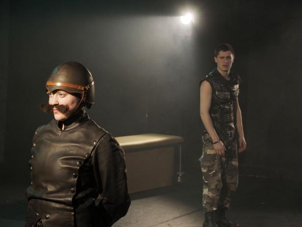 Zwei Schauspieler stehen auf einer Bühne in Kostümen.