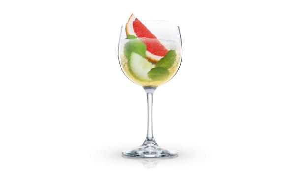 Ein Cocktail in einem Weinglas, garniert mit Grapefruit, Limette und Minze.