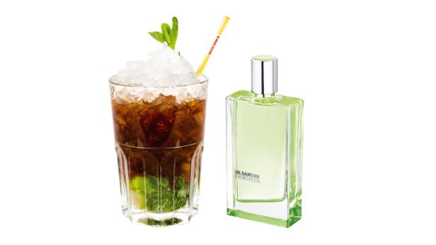 Ein Cocktail mit Eis und Minze neben einer Flasche Jil Sander Evergreen Parfum.