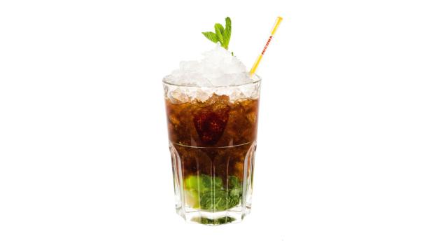 Ein Glas mit einem Mojito-Cocktail, garniert mit Minze und Eiswürfeln.