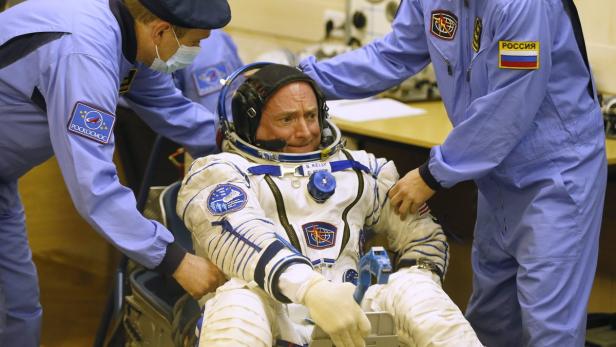 Der Astronaut Scott Kelly wird in seinen Raumanzug geholfen.