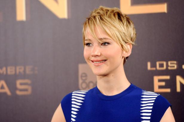 Jennifer Lawrence lächelt vor einem Werbeplakat für „Die Tribute von Panem“.