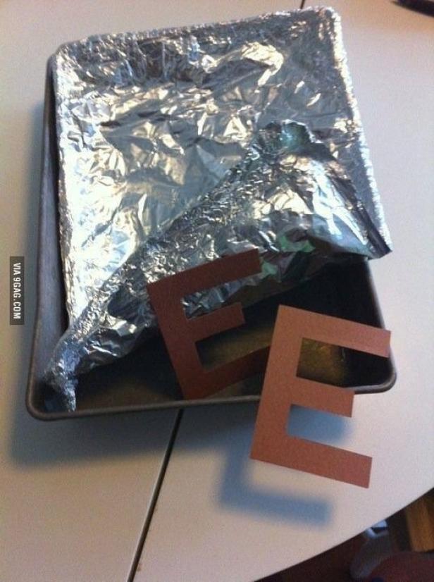 Ein mit Alufolie ausgelegtes Backblech mit zwei Buchstaben „E“ aus Papier davor.