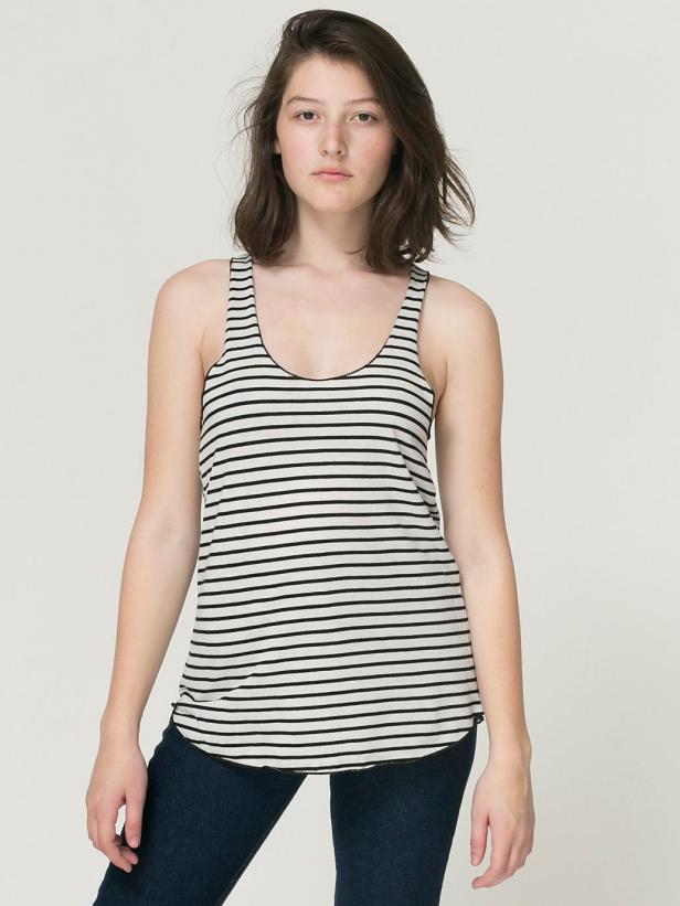 Eine Frau trägt ein gestreiftes Tanktop und dunkle Jeans.
