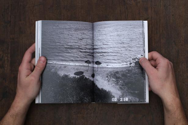 Ein aufgeschlagenes Buch zeigt eine Schwarzweißaufnahme einer Küstenlandschaft.