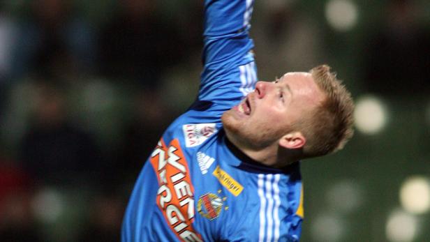 Ein Fußballspieler in einem blauen Trikot jubelt mit erhobenen Armen.