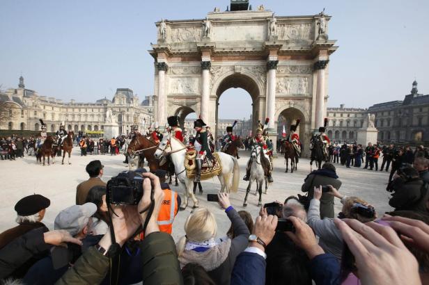 Reiter in historischen Uniformen ziehen vor dem Arc de Triomphe du Carrousel in Paris ein.