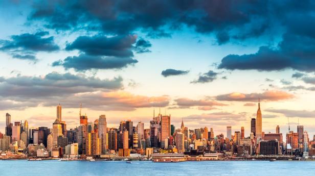 Die Skyline von New York City bei Sonnenuntergang, gesehen vom Wasser aus.