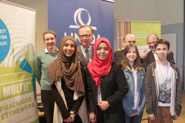 Eine Gruppe von Personen posiert vor Bannern für ein Integrationsprojekt.