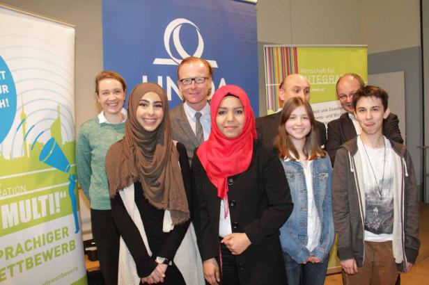 Eine Gruppe von Menschen posiert vor Bannern für einen Sprachwettbewerb.