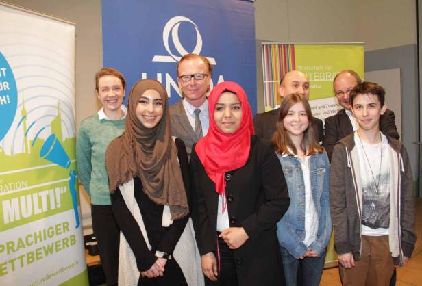 Eine Gruppe von Personen posiert vor Bannern für einen Redewettbewerb.