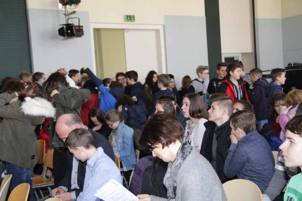 Eine Gruppe von Menschen sitzt in einem Raum und hört aufmerksam zu.